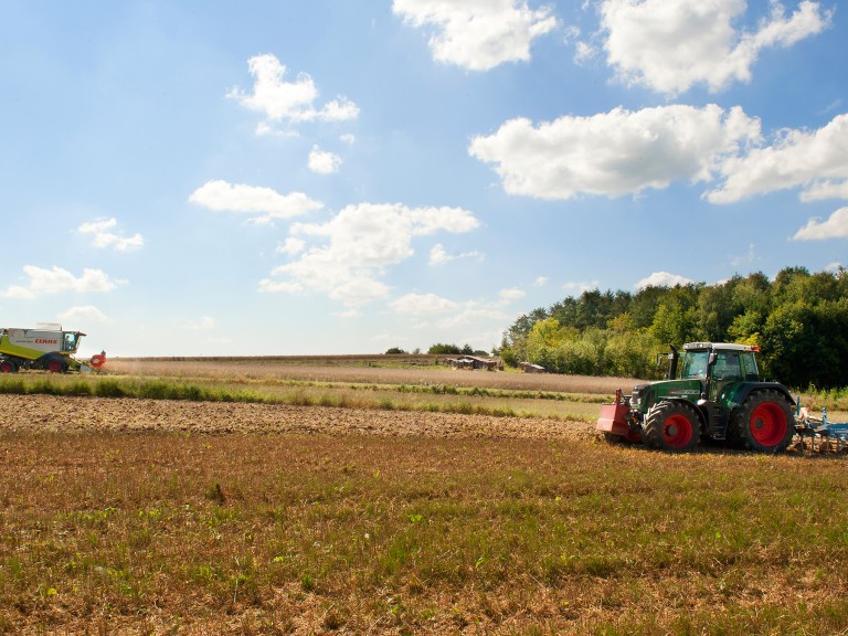 Mähdrescher und Traktor bei der Ernte auf Feldern in Bayern