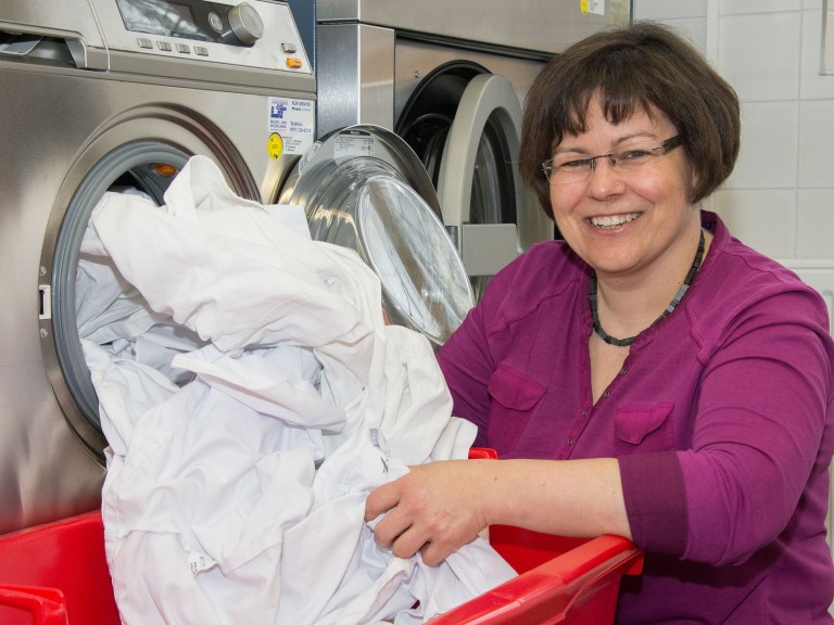 Frau sortiert Wäsche aus einer Waschmaschine