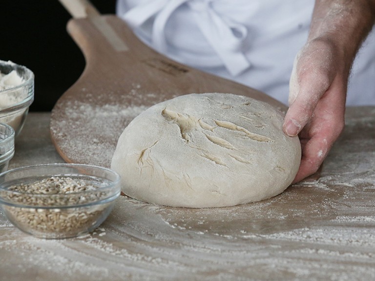 Im Backdorf bei Häussler schiebt ein Bäcker einen Laib Brot auf seinen Backschieber