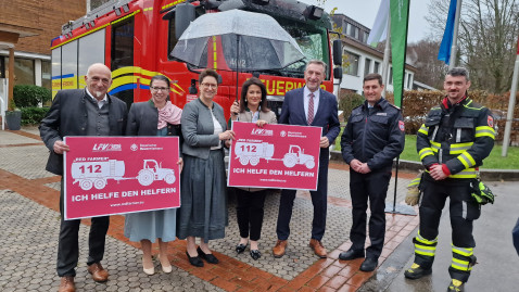 Ministerin Kaniber, Christine Singer, Gütther Felßner stehen mit Feuwehrleuten vor einem Feuerwehrauto