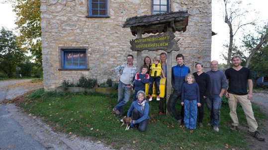 Menschengruppe steht vor Haus